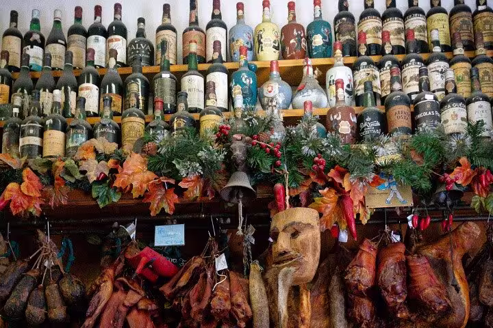 Wall of vintage Portuguese wine bottles and cured meats, capturing the essence of Porto's culinary heritage on a food tour.