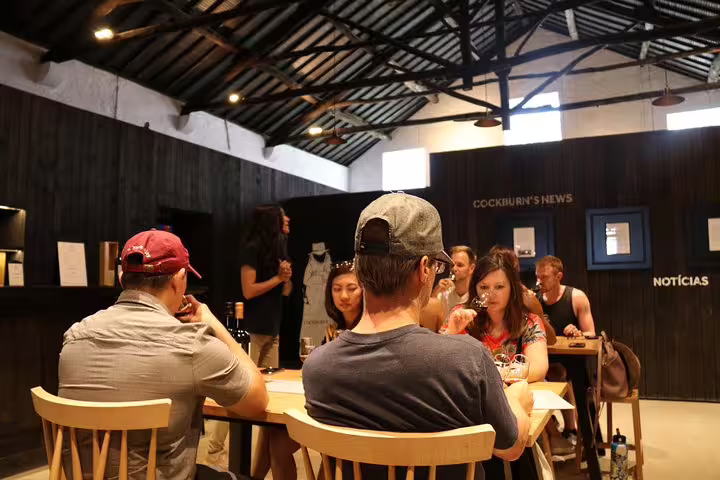 Visitors enjoy a wine tasting experience in a cozy Porto wine cellar during a private half-day city tour.