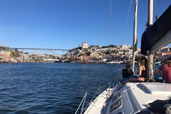Yacht cruising towards Dom Luís I Bridge on the Douro River, offering stunning views of Porto's historic architecture.