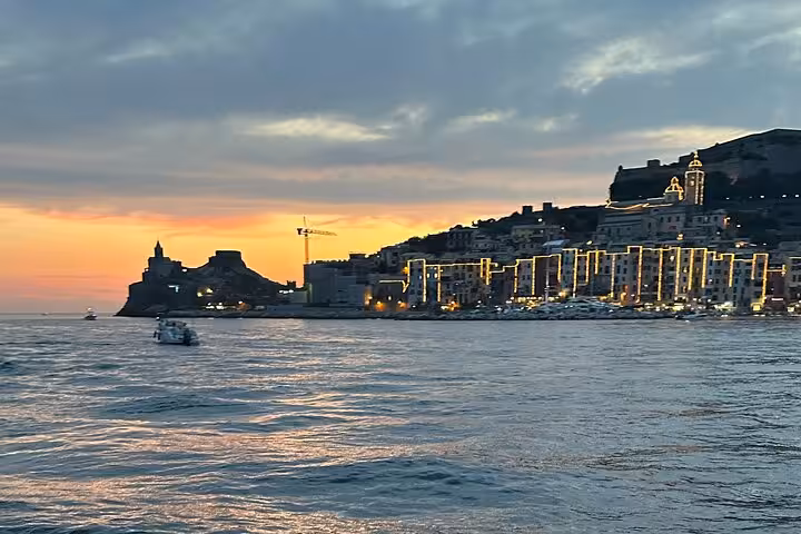 Sunset view of Portovenere with illuminated coastline from a boat tour in La Spezia, Italy.