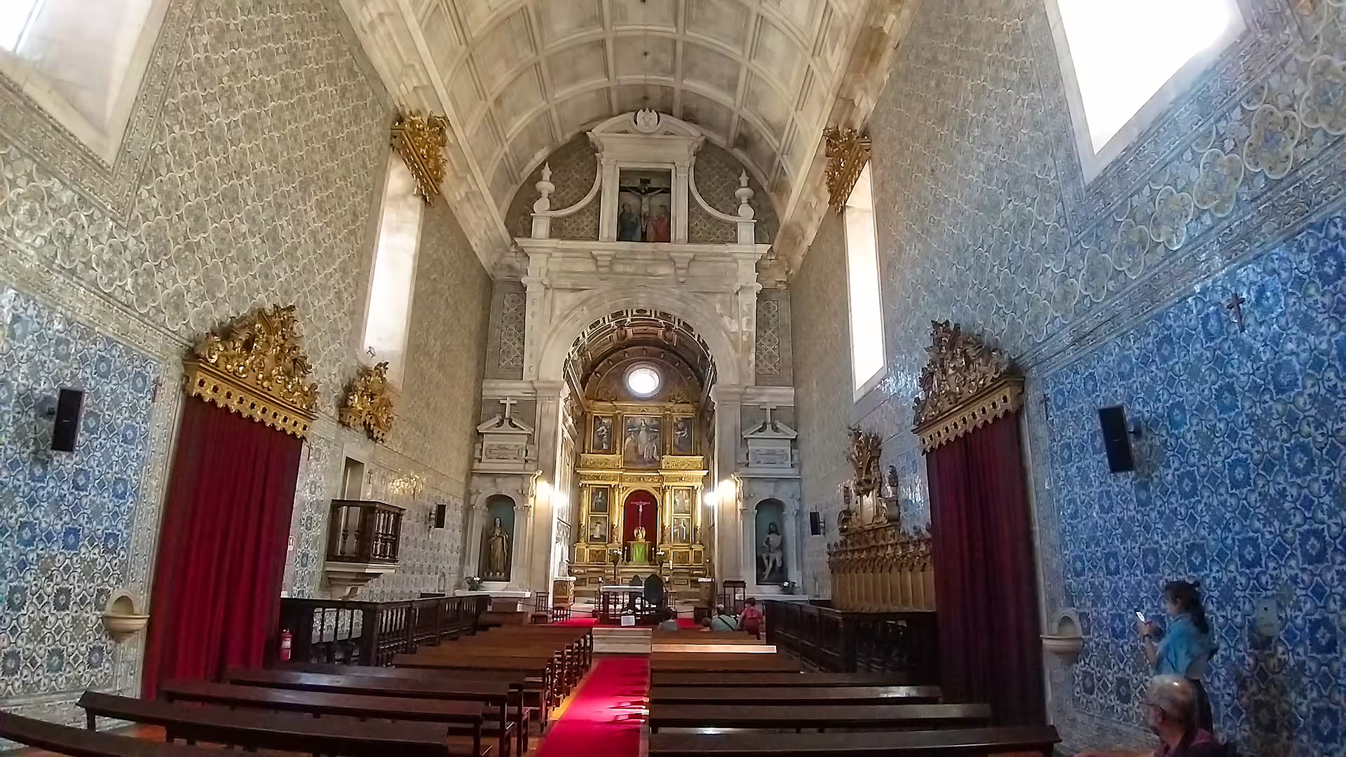 Stunning interior of a traditional Portuguese church with ornate altar and azulejo tiles, featured on Lisbon to Porto tour.