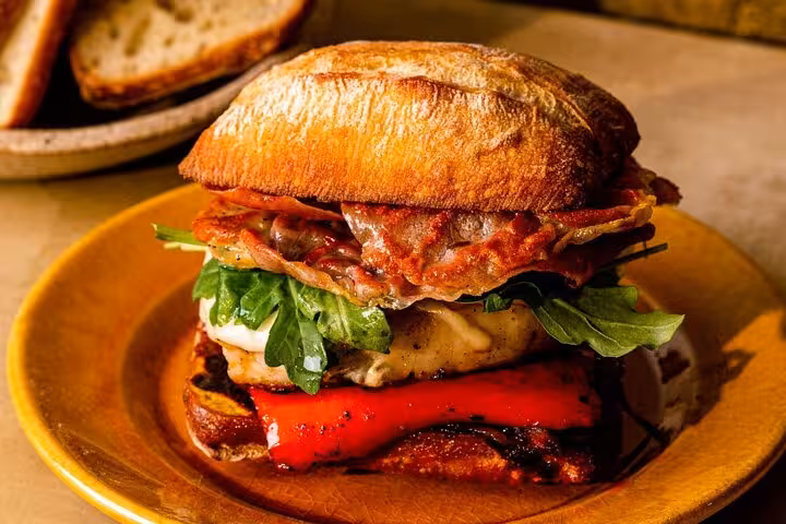 Gourmet Portuguese sandwich with cured ham, roasted peppers, and greens on ciabatta, featured in Lisbon food tour.