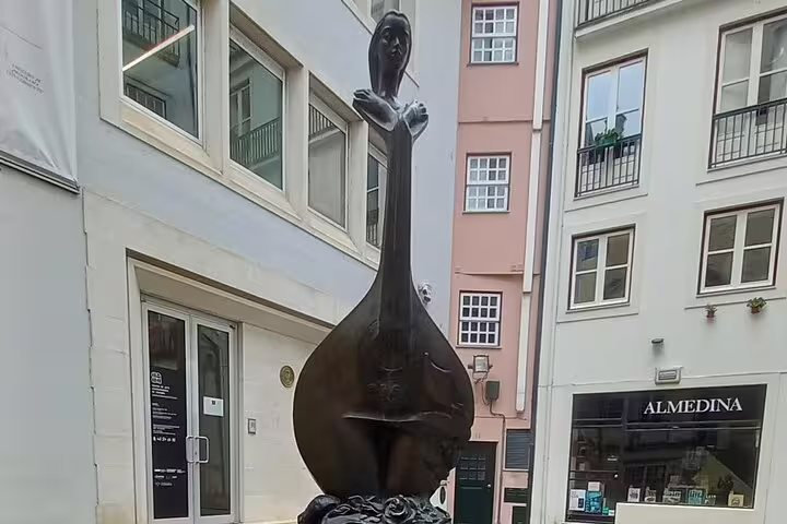 Statue of a woman holding a traditional Portuguese guitar in the streets of Coimbra on a Tomar-Coimbra tour.