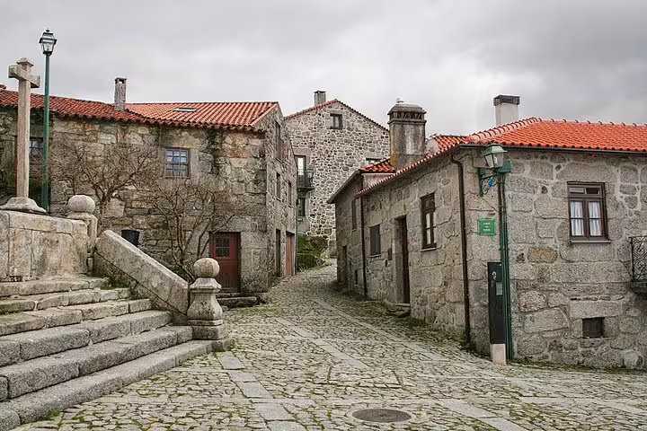 Picturesque historical village square with stone buildings and cobblestone pathways in Portugal's countryside.