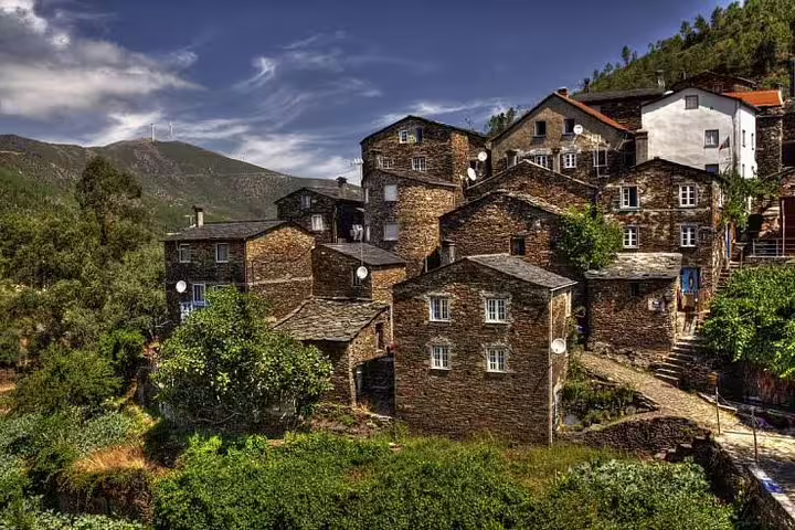 Scenic view of a Portuguese mountain village with traditional schist houses nestled among lush greenery.
