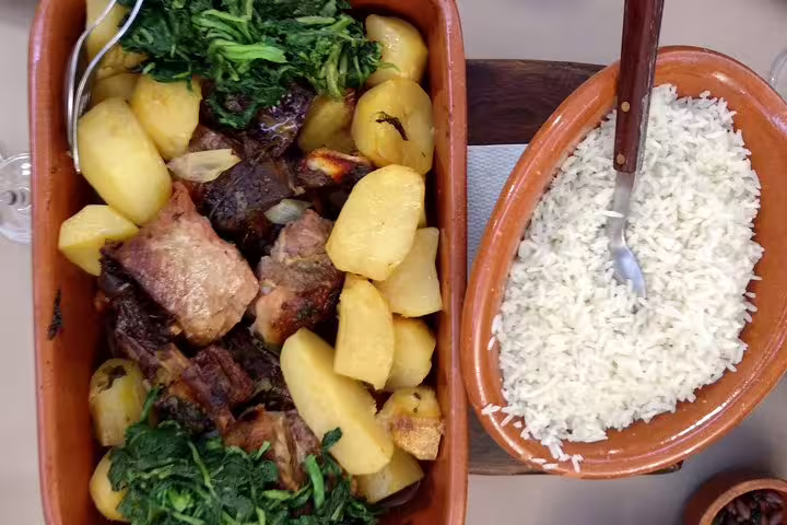 Traditional Portuguese dish with roasted meat, potatoes, and greens served alongside a bowl of fluffy white rice, part of the Aveiro and Paiva Walkways tour.
