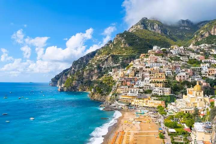 Breathtaking Positano beach scene with turquoise waters and colorful hillside buildings under a blue sky on the Amalfi Coast.