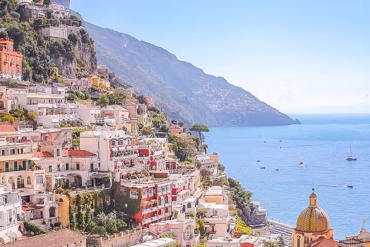 Scenic view of colorful Positano buildings cascading down the cliffside towards the sparkling Amalfi Coast waters.