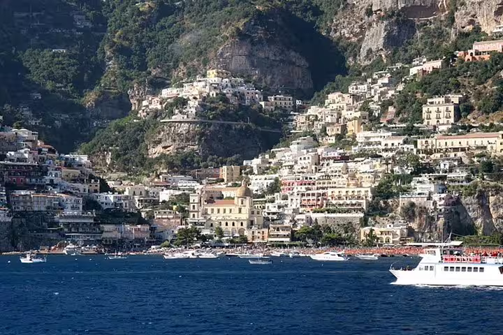 Scenic Positano coastline on the Amalfi Coast with colorful cliffside houses and boats, featured on Sorrento Positano Pompei tour