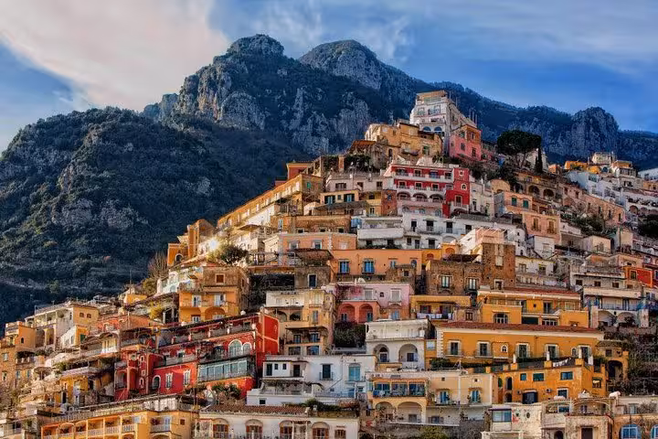 Picturesque hillside of Positano with vibrant architecture against the backdrop of lush mountains on the Amalfi Coast.