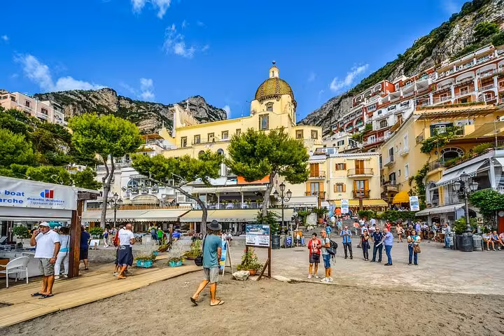 Visitors explore the vibrant streets of Positano, nestled against cliffs on the Amalfi Coast, a key Naples tour stop.