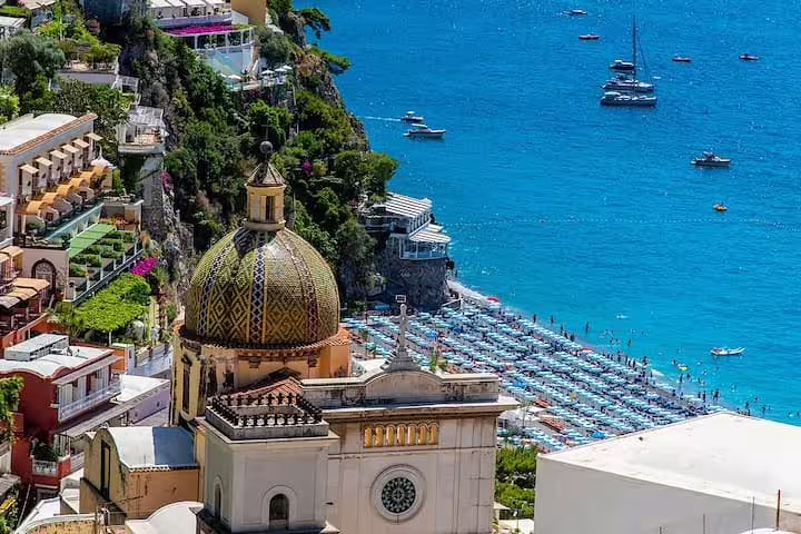 Colorful Positano houses and church dome above a busy beach and yachts on a private full day Amalfi Coast tour