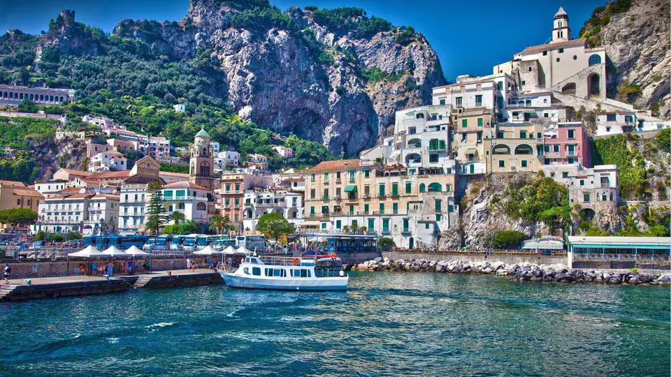 Colorful houses and a boat docked in Amalfi's picturesque harbor on the Positano sharing tour.