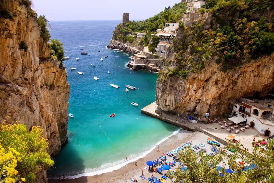 Picturesque beach and turquoise waters at a small cove near Positano, perfect for a relaxing minivan tour stop.
