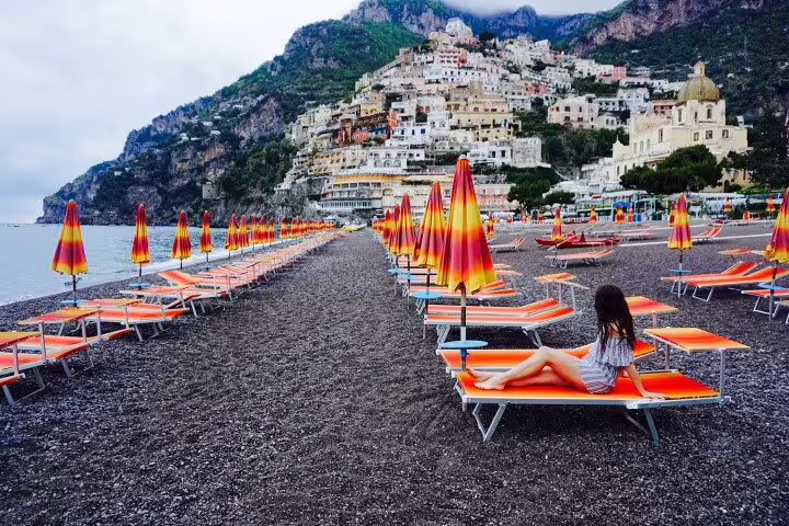 Colorful beach loungers in Positano facing hillside houses on a relaxing Amalfi Coast shore excursion private tour
