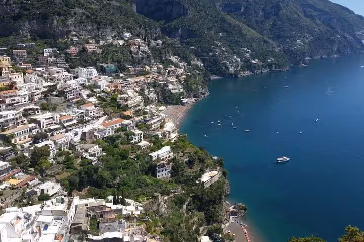 Aerial view of Positano's colorful cliffside villas overlooking the stunning blue Amalfi Coast waters on a private day tour from Sorrento.