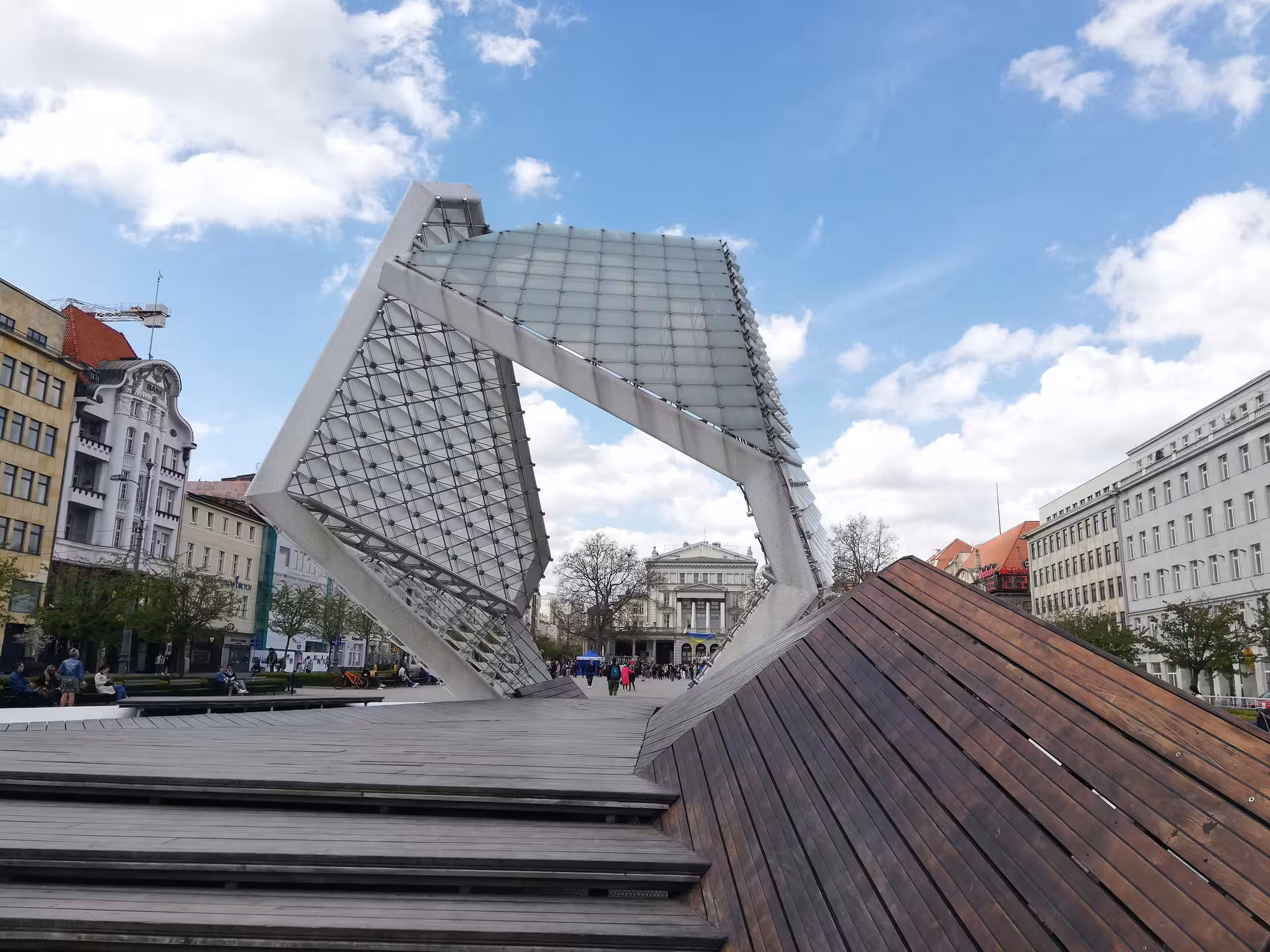 Modern glass and steel sculpture at Freedom Square Poznan with historic opera house backdrop city game tour