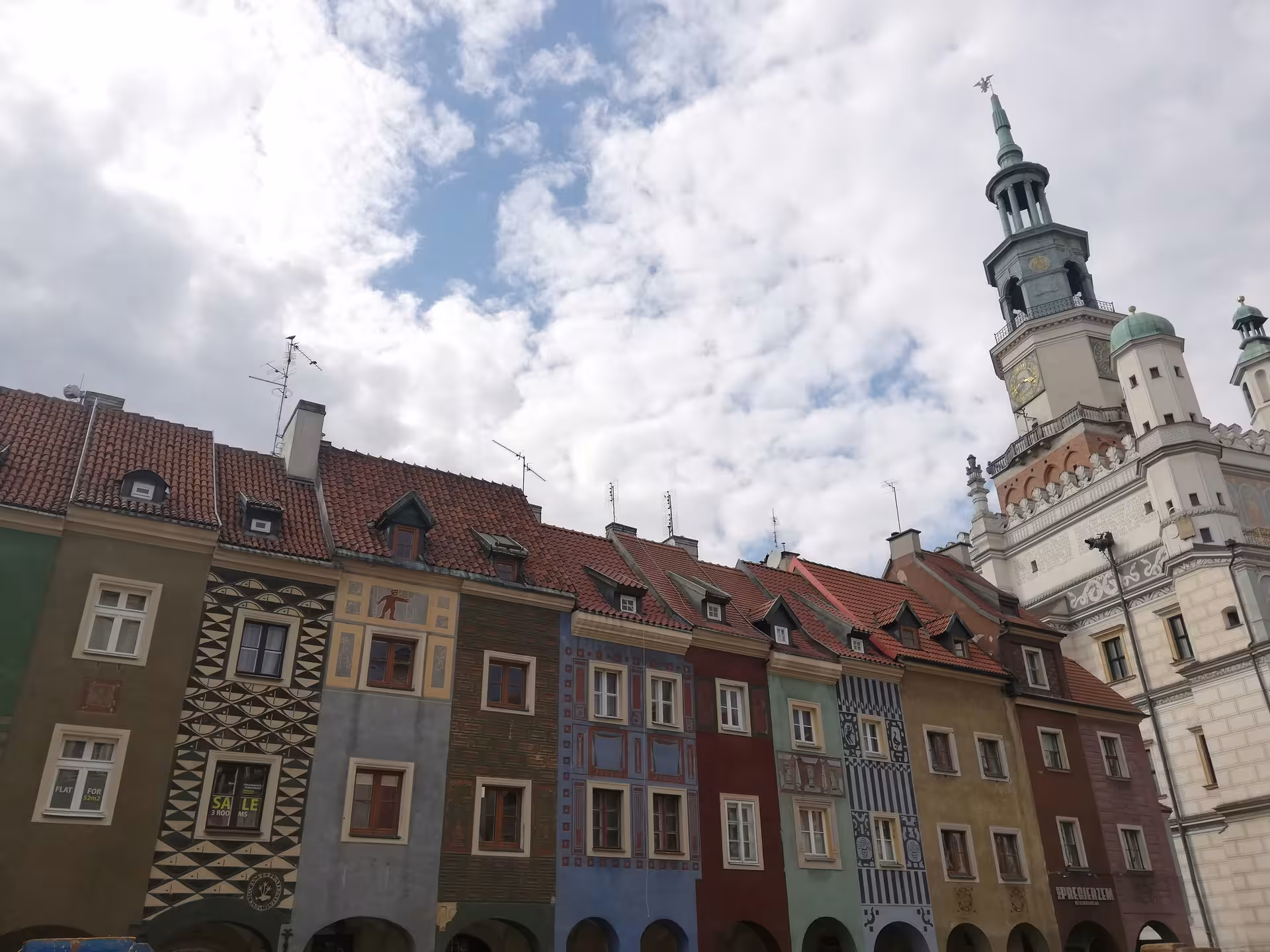 Colorful historic tenement houses lining Poznan Old Market Square with the iconic Renaissance Town Hall tower in the background