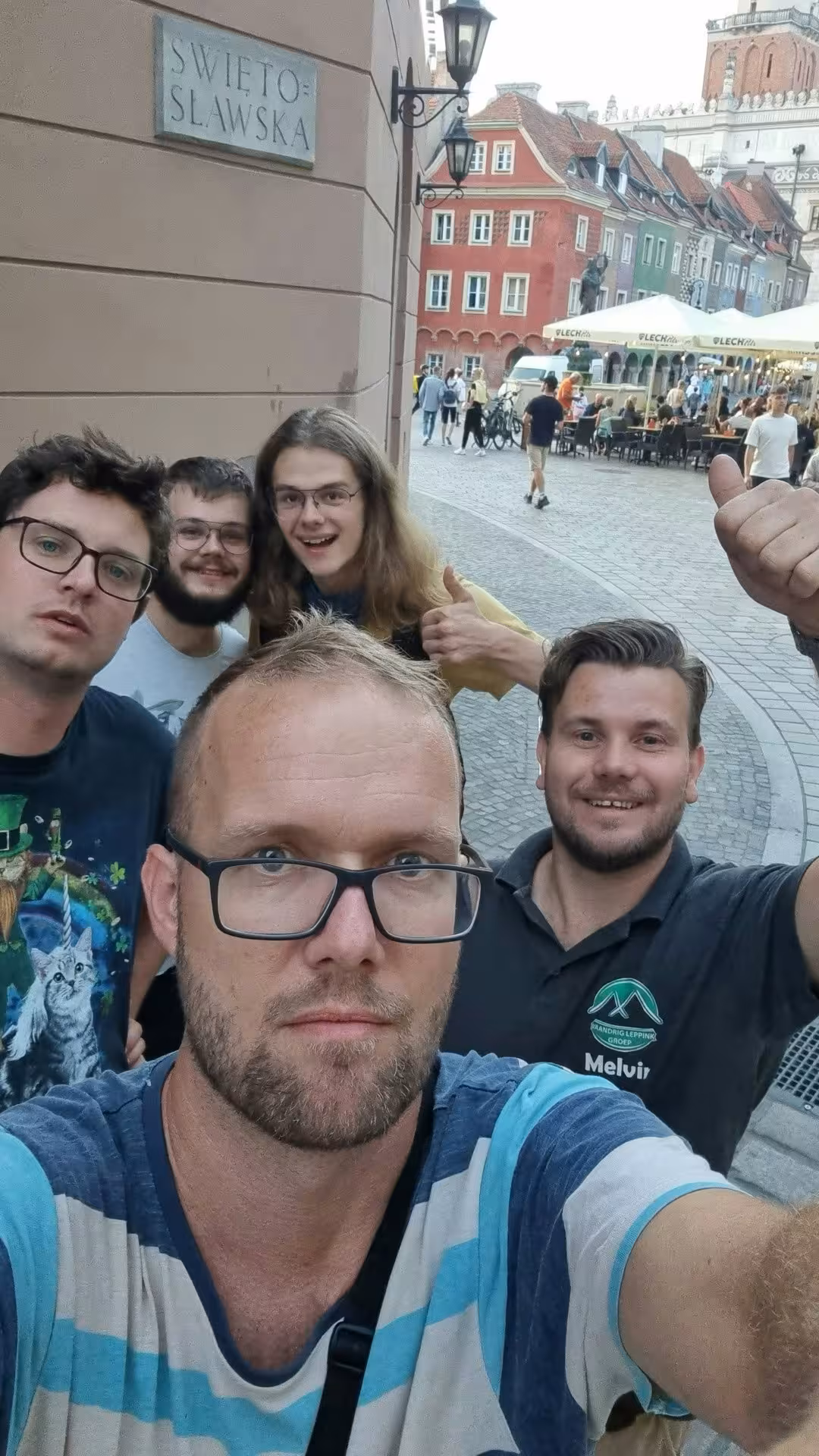 Smiling group of friends taking a fun selfie on Swietoslawska Street near Poznan Old Town market square exploration game