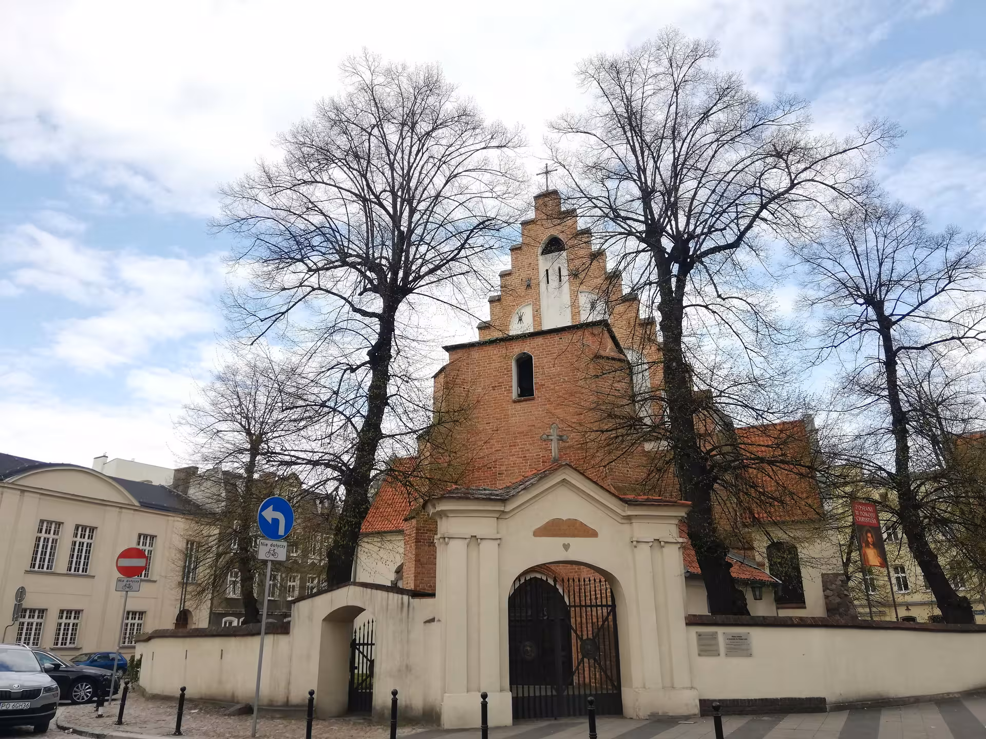 Ancient red-brick church with stepped gable tower and arched gate entrance in Poznan Old Town exploration game