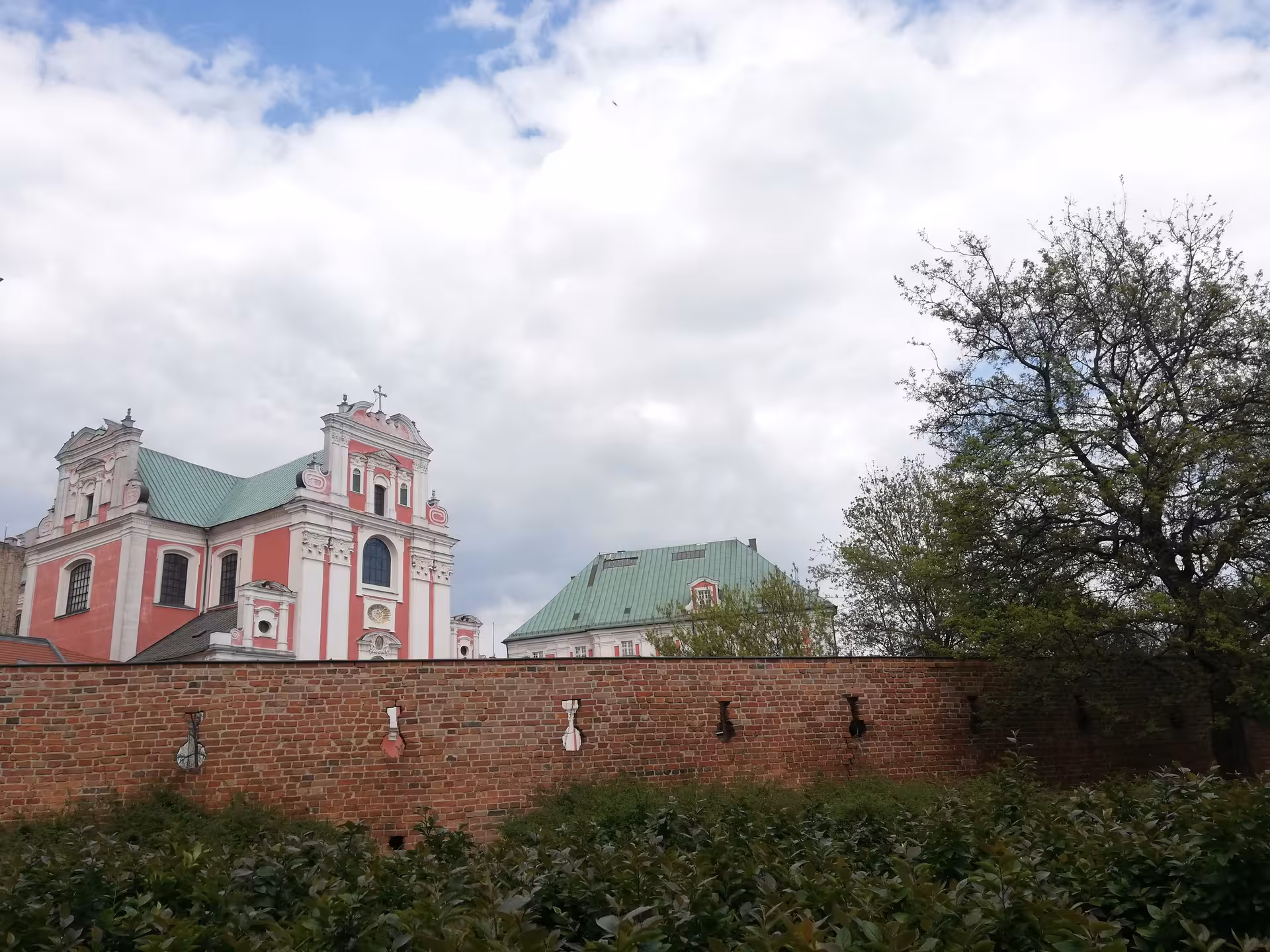 Pink baroque St. Stanislaus Church rising above ancient brick walls in Poznan Old Town highlights tour