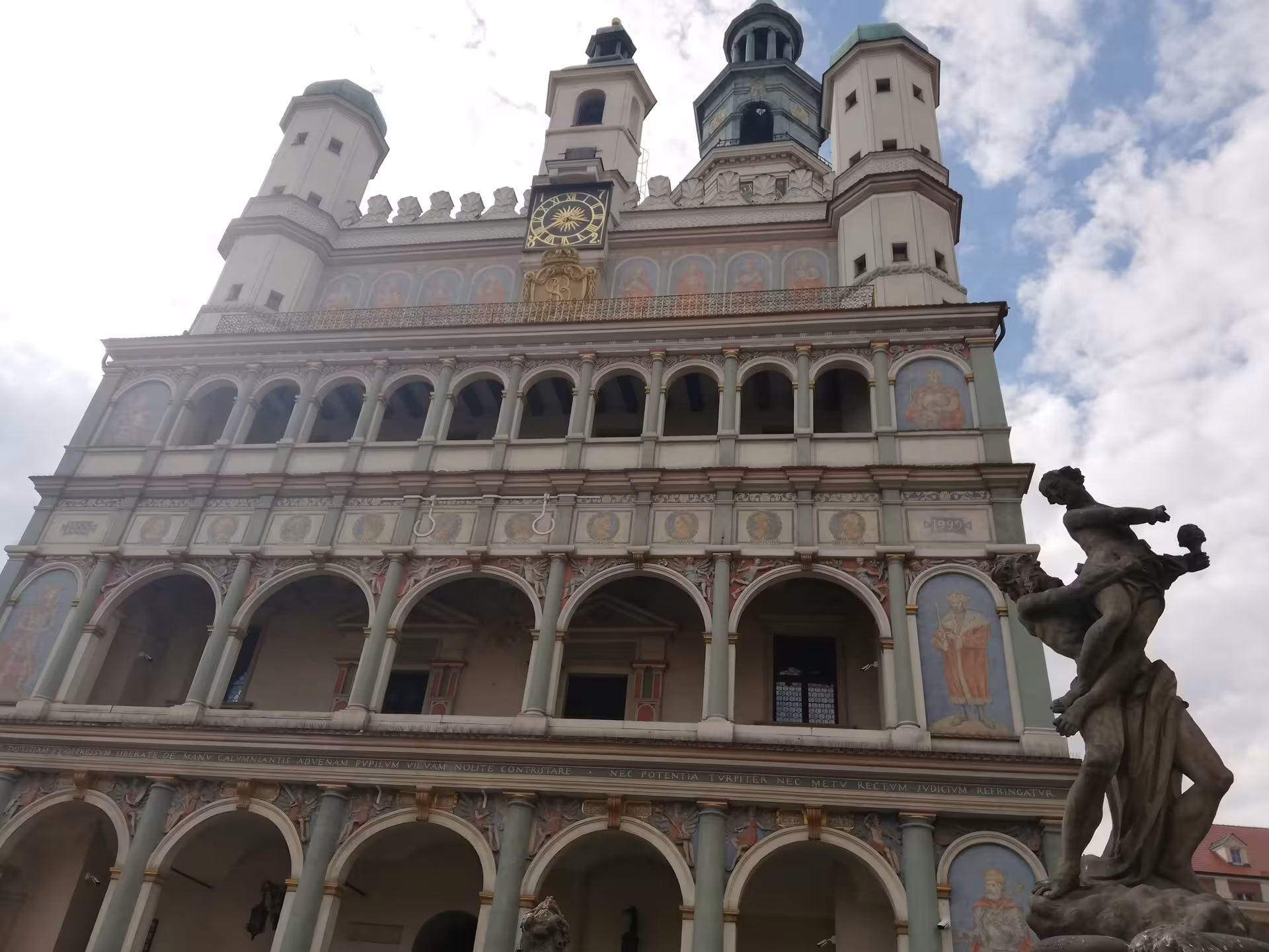 Ornate Renaissance Poznan Town Hall facade with golden clock, arched loggias, and classical sculpture on an old town highlights tour