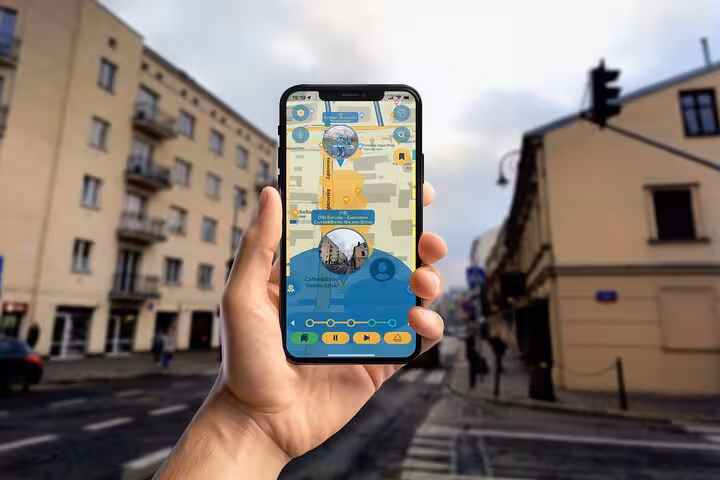 Hand holding smartphone displaying Praga District art walking tour map on a historic Warsaw street corner