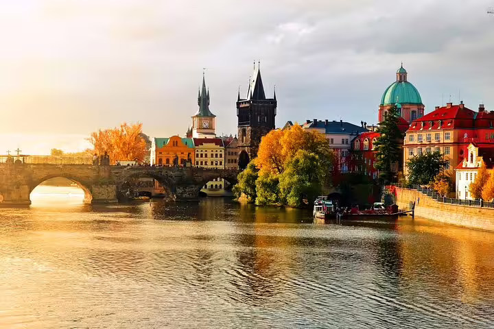 Charles Bridge and Prague Old Town skyline reflected on the Vltava River at golden sunset