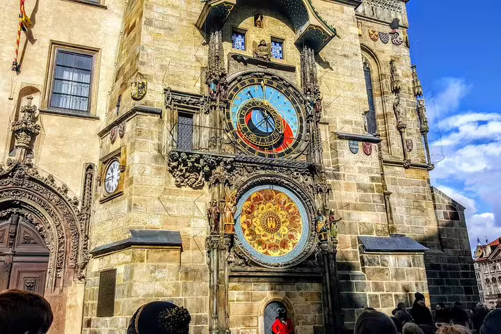 Prague Old Town Hall astronomical clock tower with ornate gothic decorations and tourists below