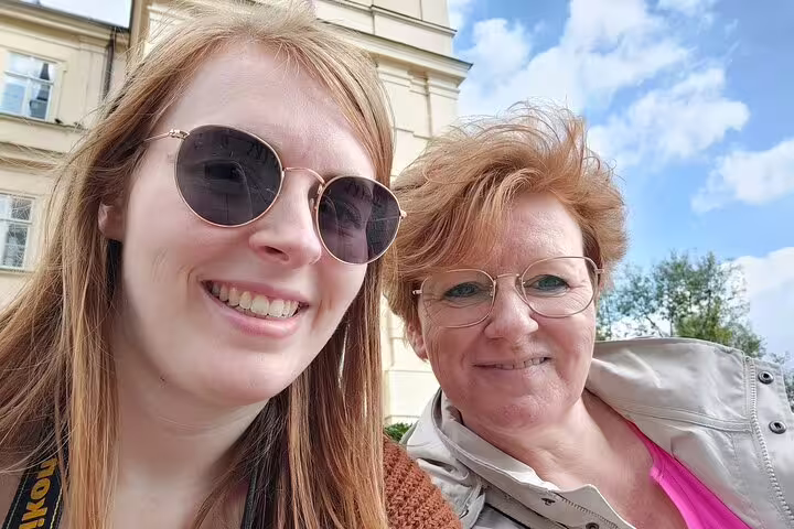 Two smiling women on a sunny day in Prague Old Town during a self-guided walking tour