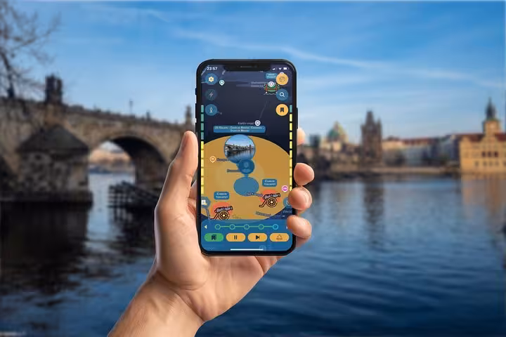 Hand holding smartphone with GPS city game app, Charles Bridge and Prague skyline in background