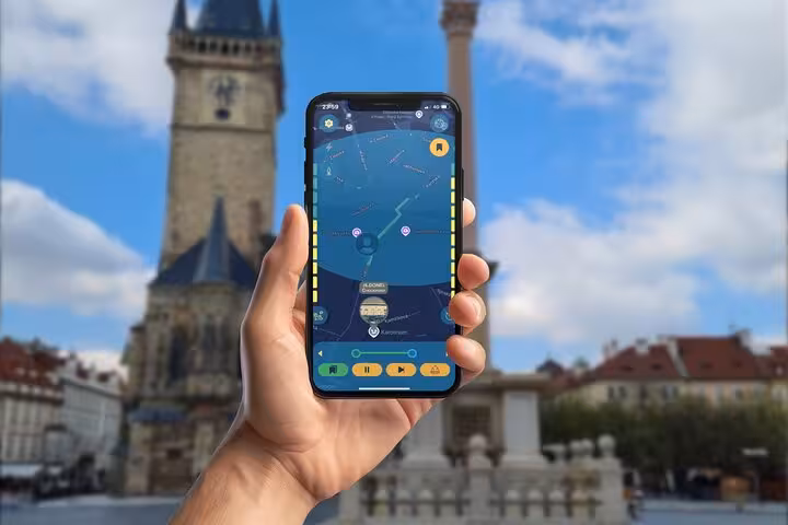 Hand holding smartphone with GPS city game map app in Prague Old Town Square with historic tower