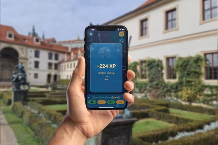Hand holding smartphone showing +224 XP completed challenge screen of Prague GPS city game tour app