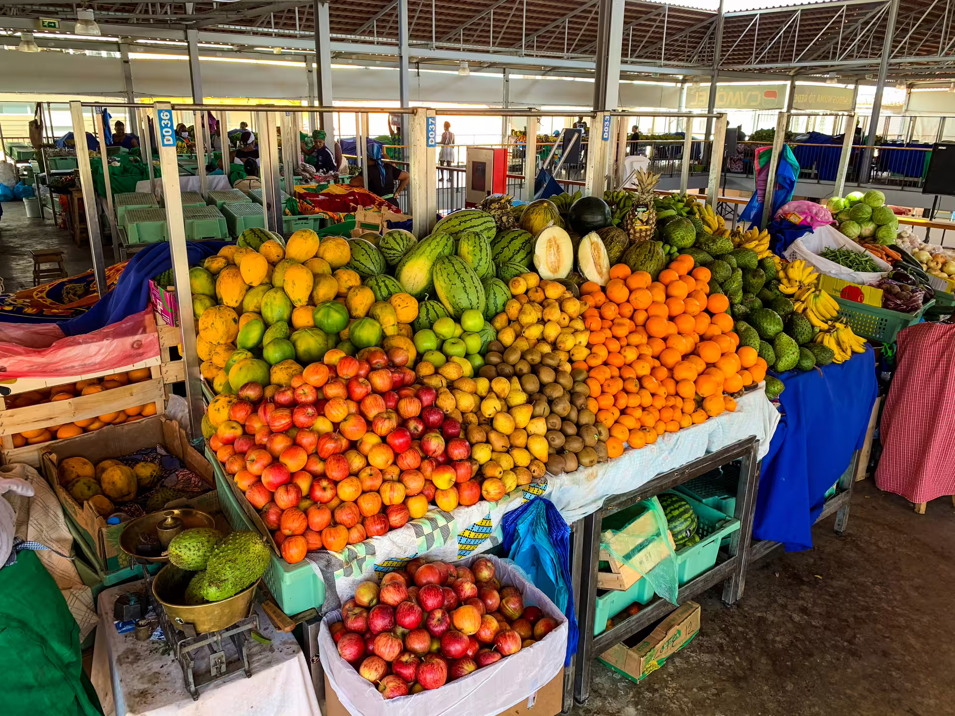 Vibrant fruit market stall in Praia featuring colorful tropical fruits like mangoes, oranges, and watermelons.