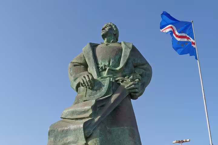 Statue under Cape Verdean flag on a sunny day in Praia, highlighting cultural heritage on a guided tour.