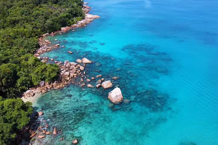 Aerial view of Praslin's turquoise waters and rocky shoreline, perfect for scenic exploration on a Seychelles day trip.