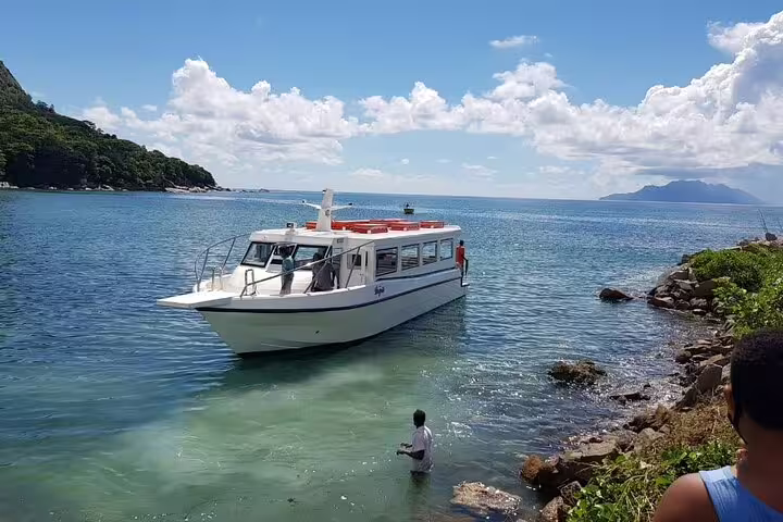A boat approaches the serene shores of Praslin, offering scenic views for the Praslin & La Digue shared day trip.