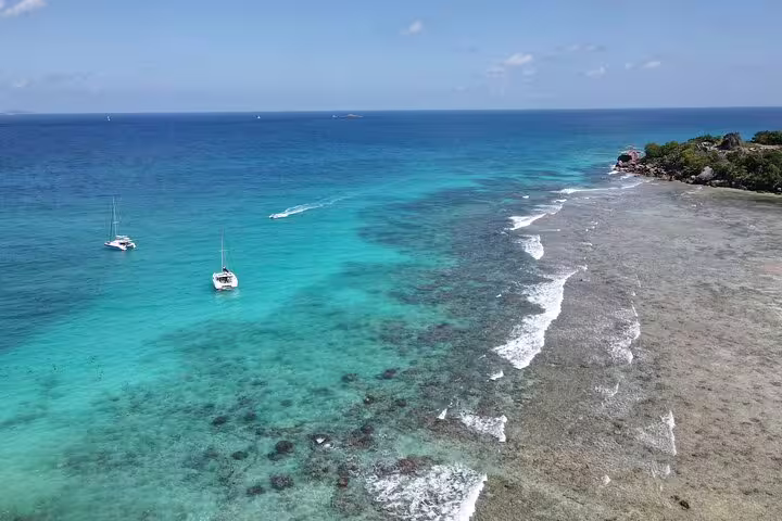 Aerial view of turquoise waters and sailboats off the coast of Praslin, perfect for a private full-day tour adventure.