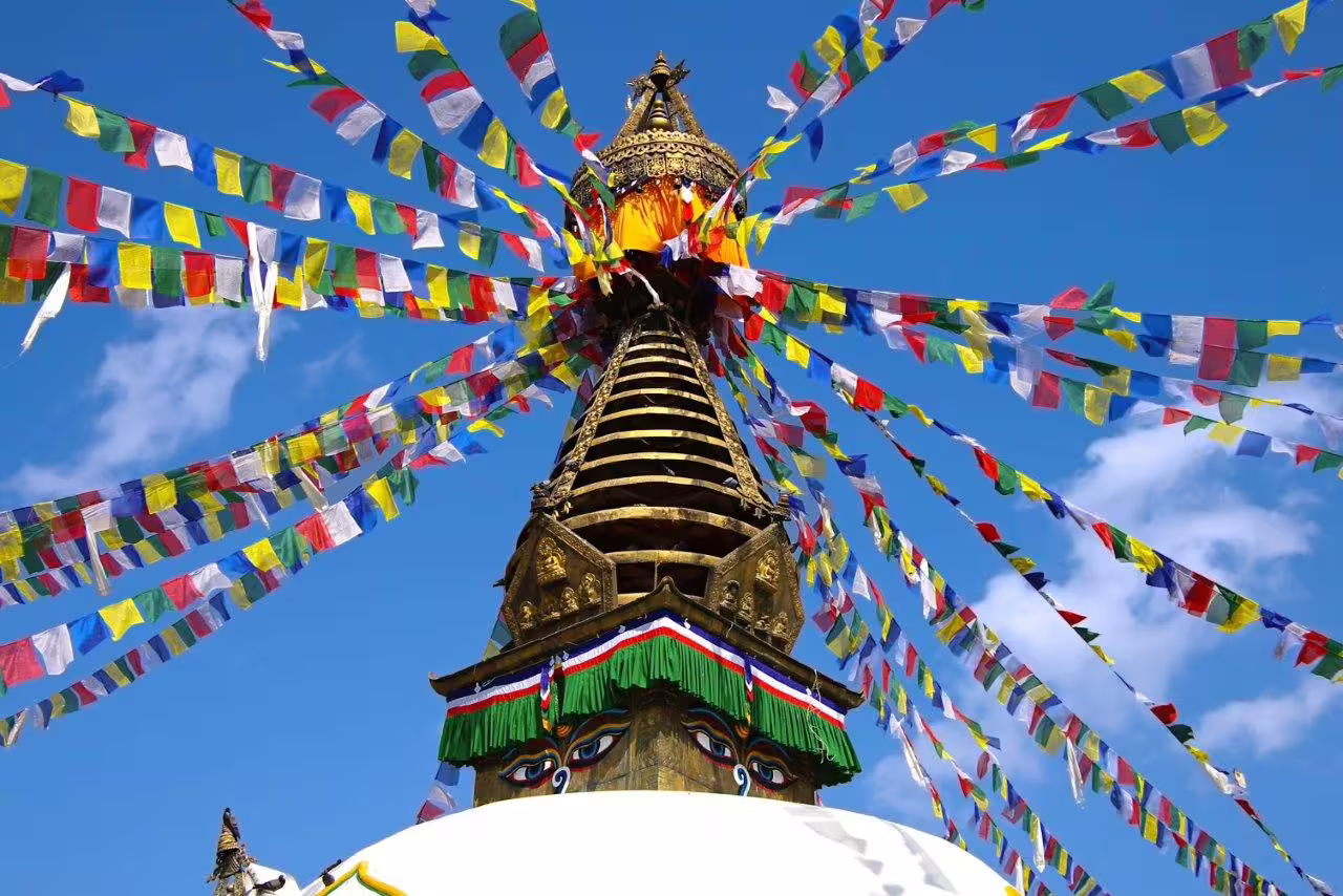 Colorful prayer flags surrounding a stupa in Kathmandu, showcasing Nepal's spiritual heritage on the tour.