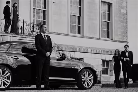 Elegant chauffeur waiting by premium car outside historic villa for VIP transfer from Naples to Pozzuoli