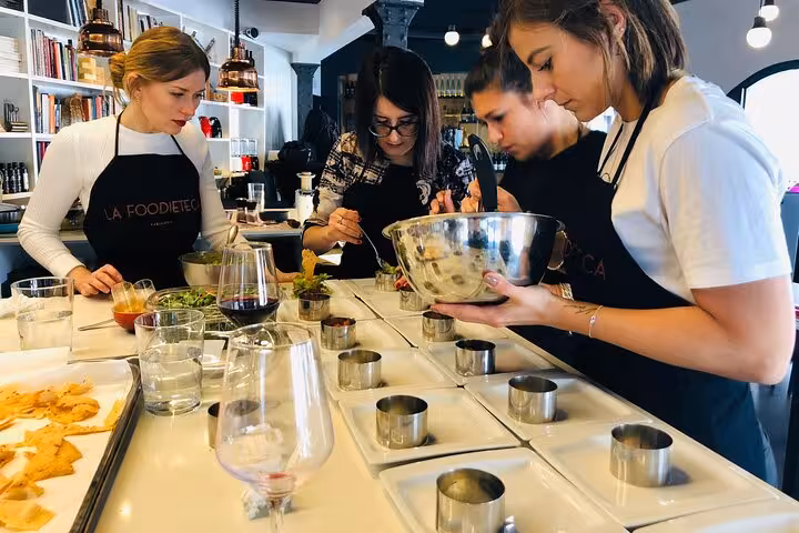 Focused group of women crafting gourmet dishes in a designer loft during a premium Spanish cooking class.