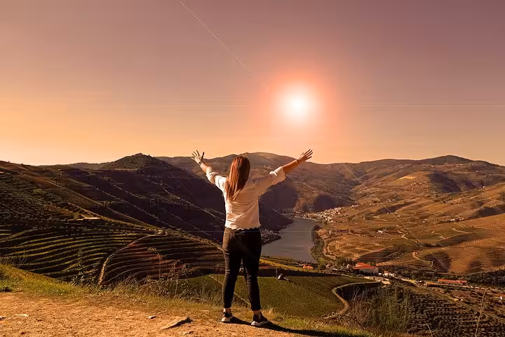 Traveler overlooking Douro Valley vineyards at sunset on a Premium Tour, scenic viewpoint and river panorama