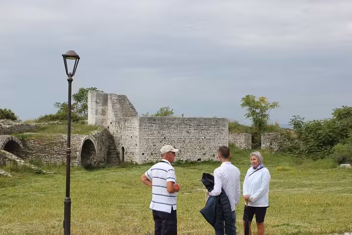 Visitors explore ancient ruins during a premium walking tour of Berat with expert guides in lush surroundings.