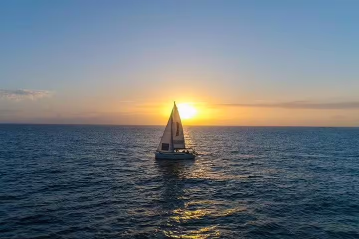 Sailboat cruising into a stunning ocean sunset on a premium private yacht charter experience.