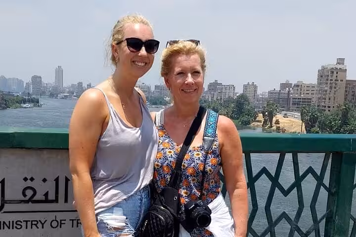 Travelers on a private 4-day Cairo tour posing by the Nile River with downtown skyline in the background