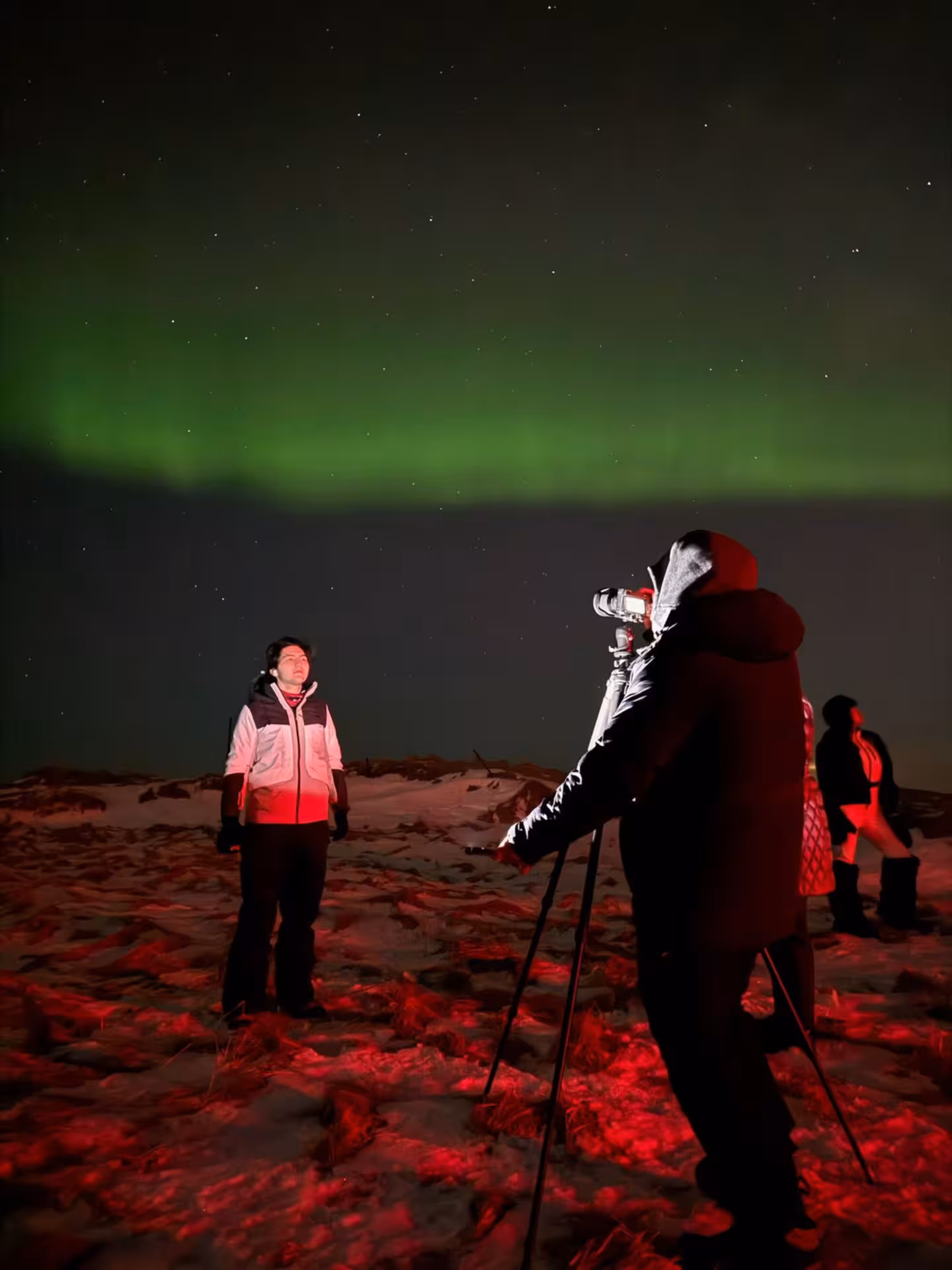 Guest posing for northern lights photos during a private guided 4x4 aurora tour from Reykjavik Iceland under starry sky