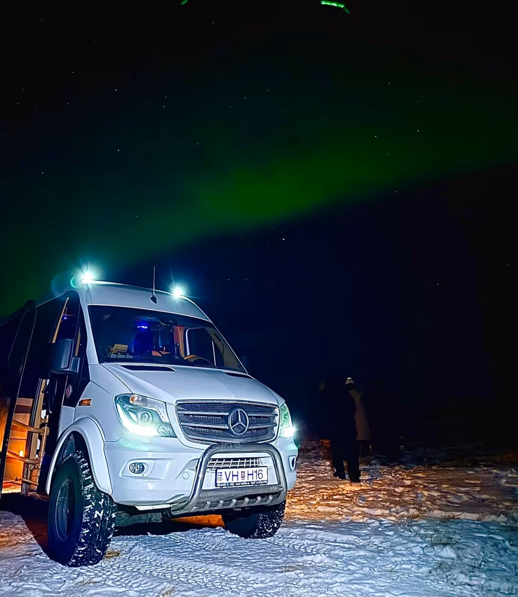 Private 4x4 super jeep parked under glowing northern lights on a guided Iceland aurora tour from Reykjavik
