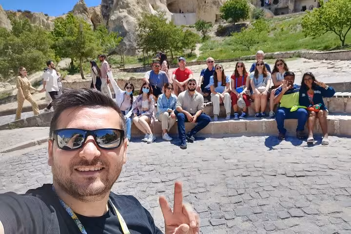 Private 6-day Turkey highlights tour group in Cappadocia, resting at Göreme viewpoint with cave rocks behind
