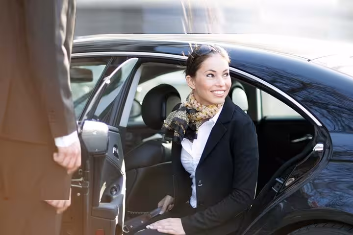 Meet and greet driver assists guest into air-conditioned private car for Hurghada airport hotel transfer