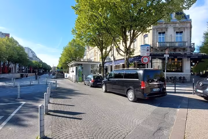 Black Mercedes van parked on a tree-lined boulevard in Paris near a hotel restaurant lounge